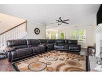 Inviting living room featuring a large sectional sofa, fireplace, and ceiling fan, perfect for relaxing and entertaining at 3885 Weeping Willow Ln, Loganville, GA 30052