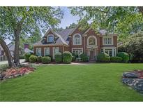 Beautiful two-story brick home boasts a manicured lawn and mature trees at 765 Vinings Estates Se Dr, Mableton, GA 30126