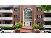 Brick condo building with large arched window, manicured landscaping, and covered balconies provides inviting curb appeal at 107 Ridley Howard Ct, Decatur, GA 30030
