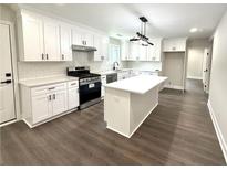 Modern kitchen features white cabinets, stainless steel appliances, and a center island at 6205 Hudson Nw St, Covington, GA 30014