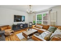 Bright living room features a brown leather sofa, modern lighting, and a view to the outside at 1634 Ponce De Leon Ne Ave # 208, Atlanta, GA 30307