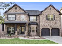 Charming brick two-story home featuring a two-car garage and covered front porch at 1023 Bentley Estates Dr, Dacula, GA 30019