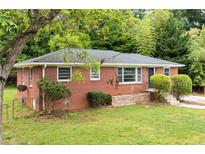Charming red brick home featuring a well-maintained lawn and mature trees offering shade and curb appeal at 2078 Olive Springs Se Rd, Marietta, GA 30060