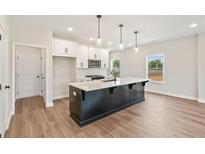 Modern kitchen features a large island with quartz countertops, white cabinetry and stainless steel microwave at 4523 Moray Dr, Mableton, GA 30126