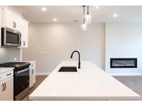 Modern kitchen with stainless steel appliances, white cabinets, island with seating, and a cozy fireplace at 4523 Moray Dr, Mableton, GA 30126