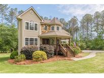 Charming two-story home featuring a stone facade, a inviting front porch, and a well-manicured lawn at 830 Hightower Trl, Oxford, GA 30054