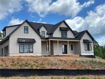 Stunning new construction featuring board and batten siding, dark window trim, and a covered front porch at 1089 Mount Carmel Church Ln, Canton, GA 30114