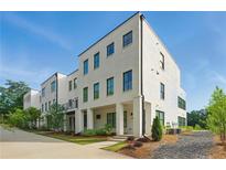 Modern townhome with a white painted brick exterior and black framed windows, complemented by lush landscaping and a blue sky at 2150 Tidwell Ln # 5, Atlanta, GA 30318