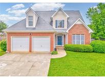 Charming brick home featuring a two-car garage, well-maintained lawn, and inviting blue front door at 1016 E Bay Springs Dr, Villa Rica, GA 30180