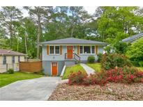 Charming bungalow with orange doors and shutters and landscaping at 569 Woods Nw Dr, Atlanta, GA 30318