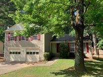 Traditional home featuring a two-car garage, complemented by mature trees and lush landscaping at 615 Barrington Way, Roswell, GA 30076