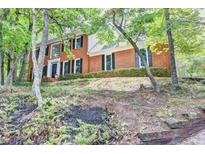 Traditional two-story brick home surrounded by mature trees and lush landscaping at 1825 Crescent Rdg, Cumming, GA 30041