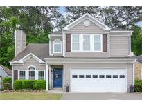Charming two-story home featuring a blue front door, two-car garage, well-manicured lawn and traditional architectural details at 3381 Grovewood Ln, Duluth, GA 30096