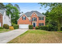 Charming two-story brick home with landscaped lawn, attached garage, and inviting dark blue front door at 7035 Hampton Bluff Way, Roswell, GA 30075