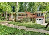 Charming brick home featuring a front-facing garage, stone walkway, and professionally landscaped yard at 2167 Tanglewood Rd, Decatur, GA 30033