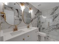 Modern bathroom featuring marble walls, double vanity, gold fixtures, and a glass-enclosed shower at 1095 Lyndhurst Way, Roswell, GA 30075