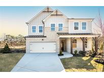 Charming two-story home with a white brick facade, a covered porch with stone pillars, and a two-car garage at 5121 Hillside Haven Drive, Powder Springs, GA 30127