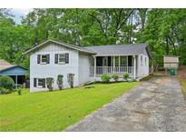 Charming exterior view of white painted home with inviting front porch and landscaped yard at 1118 Creekdale Dr, Clarkston, GA 30021