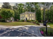 Lovely two-story home with a well-manicured lawn, mature trees, and a circular driveway at 222 Mossy Pl, Alpharetta, GA 30005