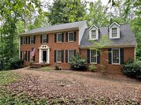 Charming two-story red brick home with black shutters, dormer windows, and a well-maintained front yard at 3741 Windhurst Dr, Lilburn, GA 30047
