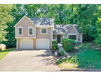 Charming two-story home features a two-car garage and a welcoming front entrance with lush landscaping and mature trees at 804 Rose Creek Walk, Woodstock, GA 30189
