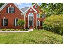 Charming two-story red brick home with lush green lawn and mature trees at 3014 Volland Grove Trail, Lawrenceville, GA 30043