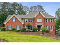 Beautiful two-story brick home with a manicured lawn and mature trees, giving it a welcoming curb appeal at 9545 Kingston Crossing Cir, Alpharetta, GA 30022