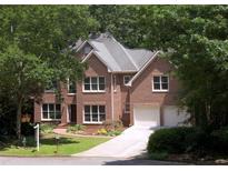 Charming two-story red brick home with a well-manicured lawn, beautiful trees and a driveway leading to a two-car garage at 1243 Williamswood Pointe, Decatur, GA 30033