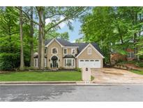 Charming two-story home featuring a well-manicured lawn, a two-car garage, and a neatly designed driveway at 910 Kings Arms Way, Alpharetta, GA 30022