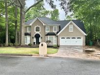 Charming two-story home with attached two-car garage and well-manicured front yard at 910 Kings Arms Way, Alpharetta, GA 30022