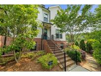 Charming two-story townhome with brick accents, landscaped yard, and inviting staircase leading to the entrance at 219 Phillips Ln, Alpharetta, GA 30009