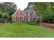 Charming brick home features a manicured lawn, black shutters, and lush landscaping at 5010 Bonnie Way, Roswell, GA 30075