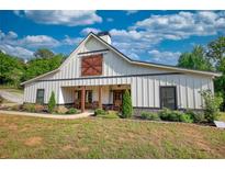Charming white farmhouse with a barn door detail and welcoming front porch with rocking chairs at 540 Benton Rd, Covington, GA 30014