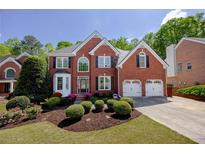 Beautiful brick home featuring a manicured front yard with flowering shrubs and a two-car garage at 1105 Anemone Nw Way, Acworth, GA 30102
