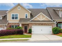 Charming townhome featuring a two-car garage, brick accents, manicured landscaping, and inviting curb appeal at 2141 Slick Stone Dr, Snellville, GA 30078
