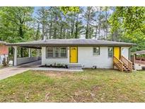 Charming ranch-style home with a bright yellow door, carport, and well-maintained lawn at 2148 Meador Se Ave, Atlanta, GA 30315