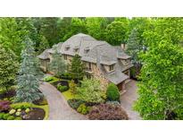 Stunning stone home with lush landscaping, a brick driveway, and a three-car garage surrounded by mature trees at 939 Middle Fork Trl, Suwanee, GA 30024