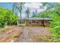 Overgrown front yard and exterior of brick house, ready to be revived with landscaping and repair at 2322 Paces Ferry Se Rd, Smyrna, GA 30080