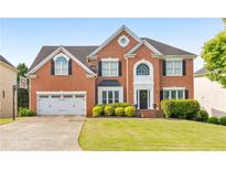 Traditional two-story brick home featuring a well-maintained lawn, two-car garage, and beautiful landscaping at 1730 Millhouse Run, Marietta, GA 30066