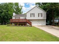 Charming two-story home with a well-maintained lawn, a wooden deck, and a two-car garage at 701 Rockingham Ct, Woodstock, GA 30189