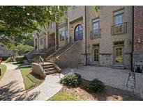 Elegant brick townhome featuring stone accents, arched entry door, and wrought iron detailing on a beautifully landscaped walkway at 538 Micayne Cir # 3, Smyrna, GA 30082