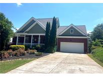 Charming single Gathering home featuring a two-car garage and a lush, landscaped front yard at 140 Puckett Creek Dr, Canton, GA 30114