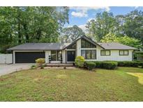 Charming exterior of a one-story home with a well-manicured lawn and mature trees at 1759 Kimberly Sw Dr, Marietta, GA 30008