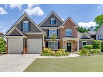 Beautiful two-story home featuring a manicured lawn, two-car garage, and welcoming front entrance at 1563 Country Wood Dr, Hoschton, GA 30548