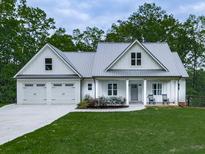 Charming home boasts a two-car garage, a metal roof, and rocking chairs on the front porch at 2700 Sam Nelson Rd, Canton, GA 30114