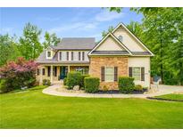Charming two-story home with stone accents, manicured lawn and mature trees at 374 Beaumont Farms Dr, Sharpsburg, GA 30277