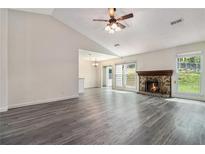 Spacious living room with wood flooring, stone fireplace, ceiling fan, and bright windows at 520 Cranberry Pl, Roswell, GA 30076