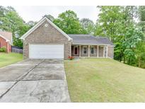 Charming brick home featuring a two-car garage and a well-manicured lawn with mature trees in a peaceful neighborhood at 2682 Freemans Walk Path, Dacula, GA 30019