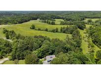Expansive aerial view of land, trees, and fields with a residence nestled in the trees at 200 Mcclure Dr, Cumming, GA 30028
