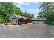 Charming home with a covered porch, stone accents, and a detached two-car garage with ample parking space at 200 Mcclure Dr, Cumming, GA 30028